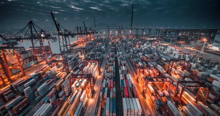 lots of shipping conatiners stacked in a storage area by some water